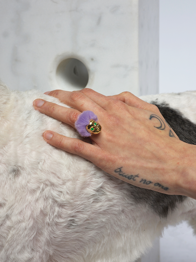 Hand wearing ALF Jewelry Baby Ring in gold vermeil with purple fur and green tsavorite eyes, luxury handcrafted ring.
