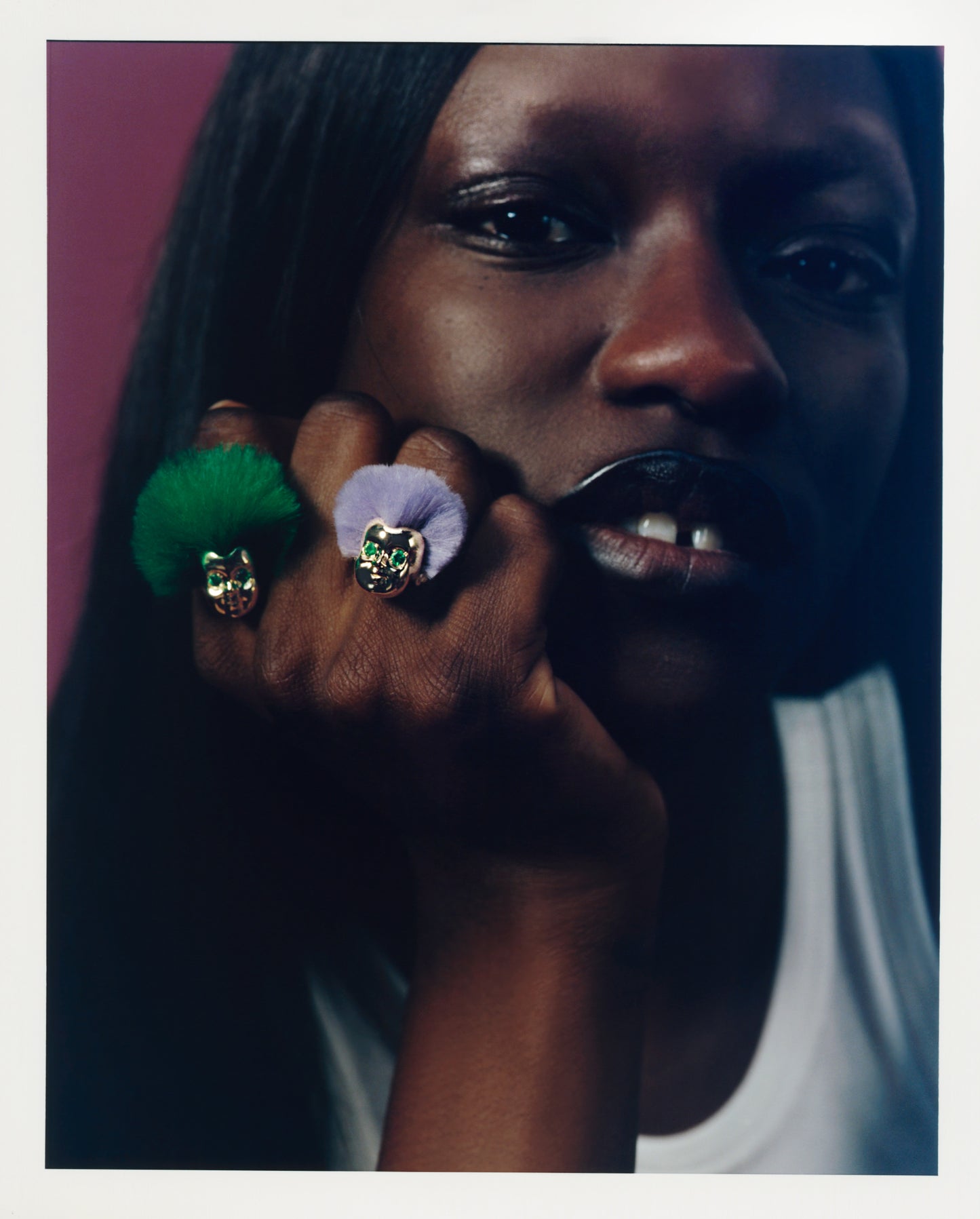 Woman wearing two ALF Jewelry Baby Rings in 18ct gold vermeil with tsavorite eyes and recycled fur in green and purple.